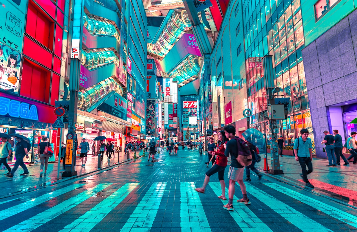Rua movimentada e iluminada no Japão à noite, com letreiros em japonês